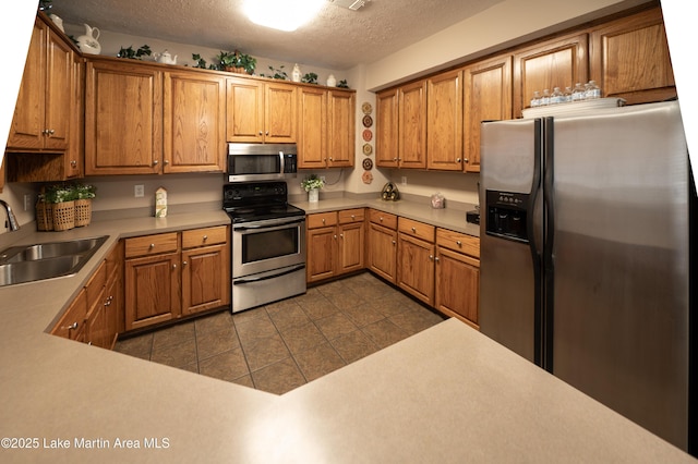 kitchen with stainless steel appliances, sink, a textured ceiling, and dark tile patterned floors