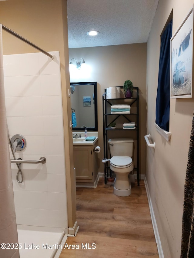 full bath featuring toilet, wood finished floors, a textured ceiling, vanity, and a shower stall