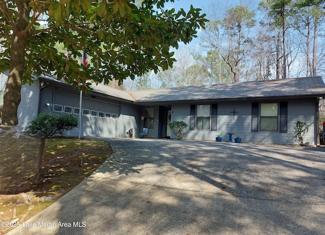 ranch-style home featuring an attached garage, driveway, and metal roof