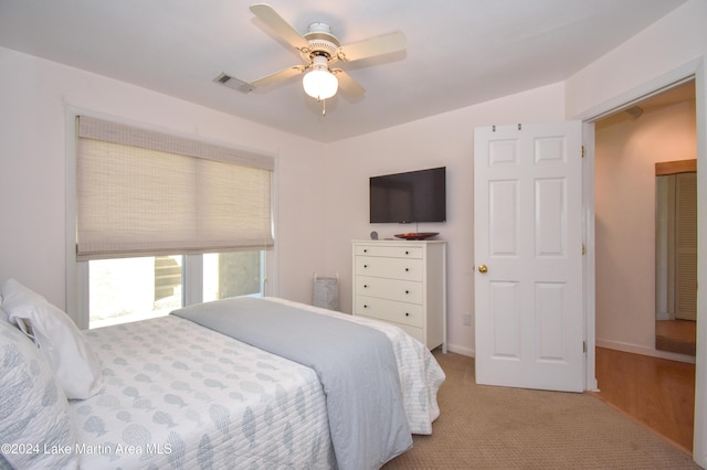 bedroom with ceiling fan, light colored carpet, and a closet