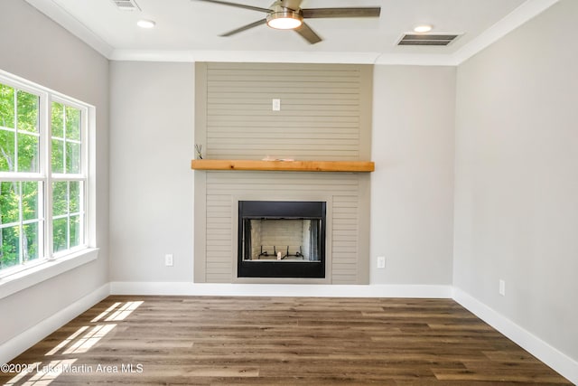 unfurnished living room with a large fireplace, a ceiling fan, crown molding, baseboards, and wood finished floors