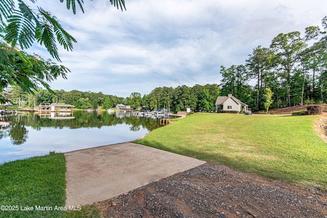 view of grassy yard featuring a boat ramp, a water view, and a dock