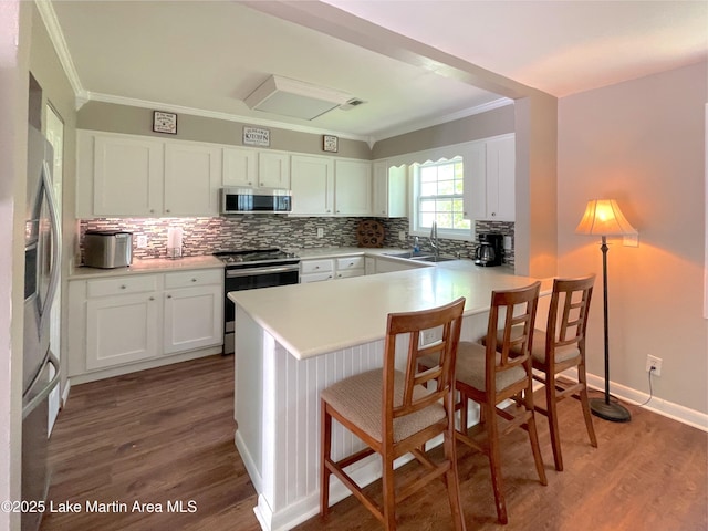 11 Redbud Ct, Dadeville, AL 36853 - kitchen with appliances with stainless steel finishes, crown molding, wood finished floors, a peninsula, and decorative backsplash