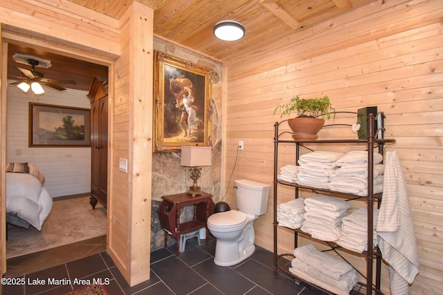 bathroom featuring ceiling fan, tile patterned flooring, wooden walls, wooden ceiling, and toilet