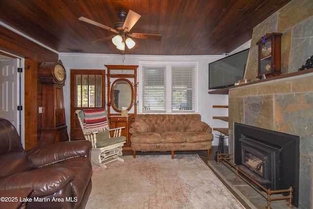 living room featuring wooden ceiling, ceiling fan, and a wood stove