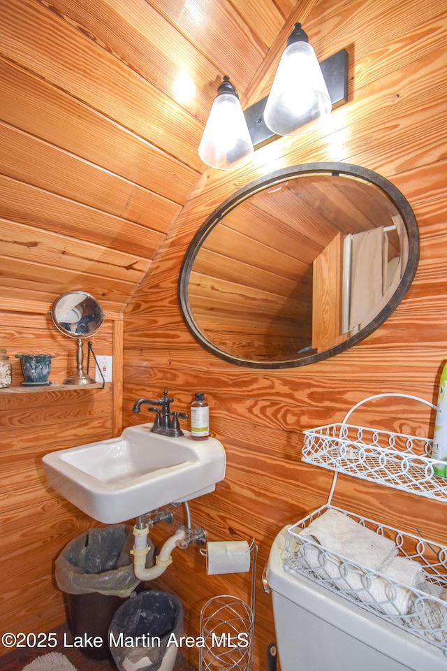 bathroom with wood ceiling, toilet, sink, and wood walls