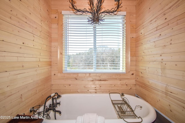 bathroom featuring a bathtub and wood walls