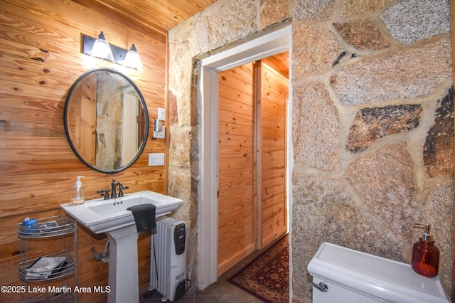 bathroom with wood walls, sink, tile patterned flooring, toilet, and wooden ceiling