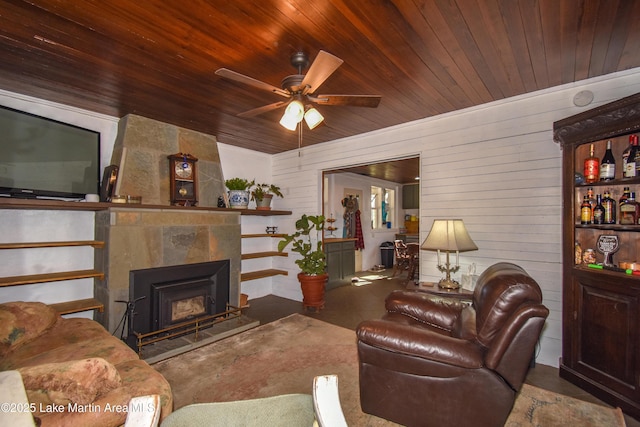 living room with a premium fireplace, ceiling fan, and wood ceiling