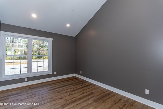 spare room featuring dark hardwood / wood-style floors and lofted ceiling