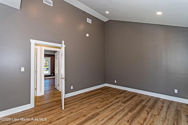 spare room with hardwood / wood-style floors and lofted ceiling