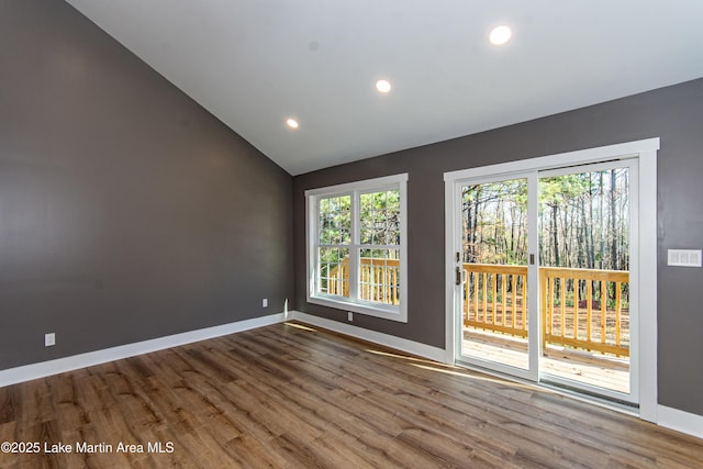 spare room featuring wood-type flooring and vaulted ceiling