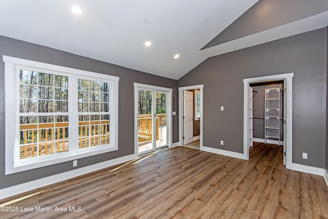 interior space featuring hardwood / wood-style floors, lofted ceiling, a spacious closet, and access to outside