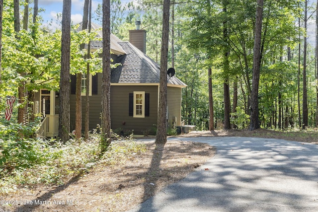 view of property exterior with roof with shingles, a chimney, and central AC unit