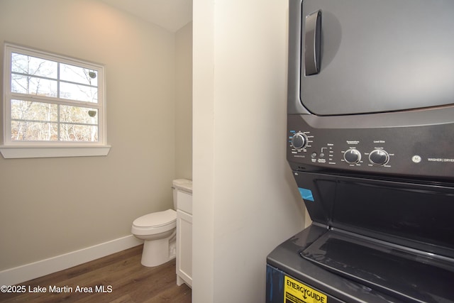 clothes washing area featuring dark hardwood / wood-style floors and stacked washer and dryer