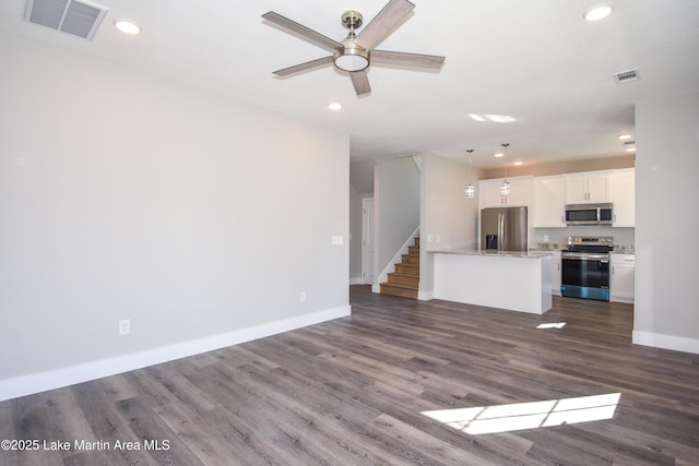 unfurnished living room with ceiling fan and dark wood-type flooring