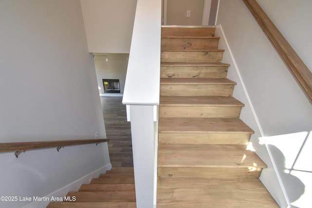 stairs with a fireplace and wood-type flooring