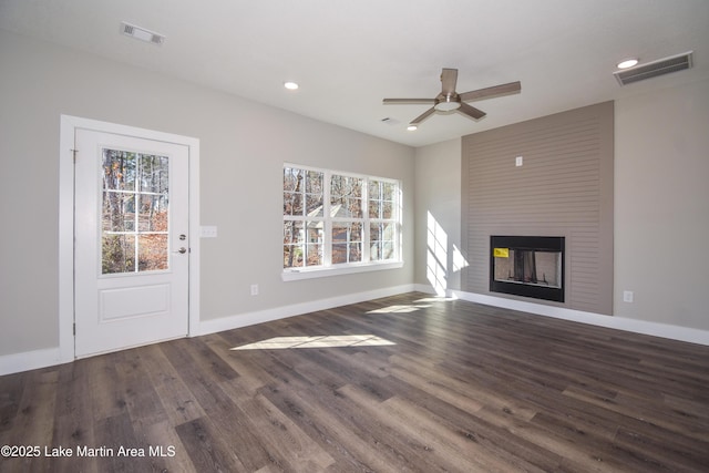 unfurnished living room featuring plenty of natural light, ceiling fan, dark hardwood / wood-style flooring, and a fireplace