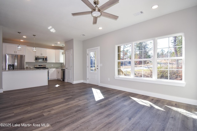 unfurnished living room featuring dark hardwood / wood-style flooring, a wealth of natural light, and ceiling fan