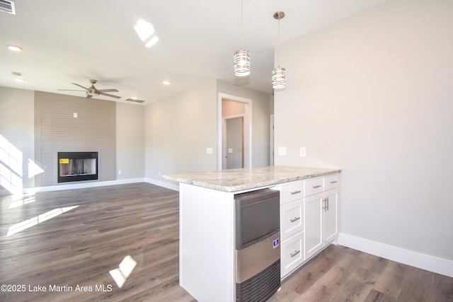 kitchen with light stone counters, a fireplace, ceiling fan, decorative light fixtures, and white cabinets