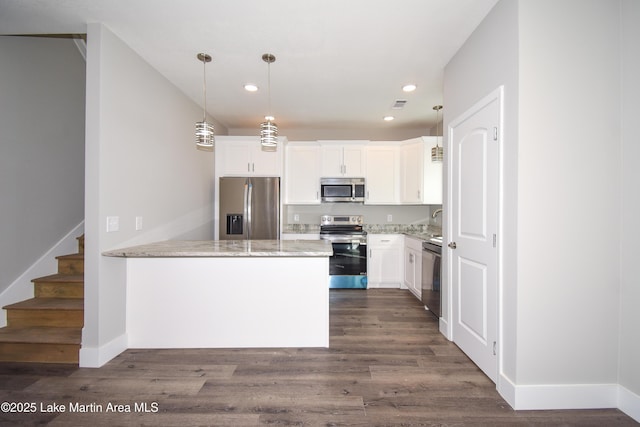 kitchen with kitchen peninsula, appliances with stainless steel finishes, decorative light fixtures, light stone counters, and white cabinetry