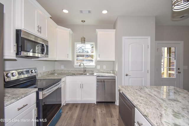 kitchen featuring white cabinets, decorative light fixtures, sink, and stainless steel appliances