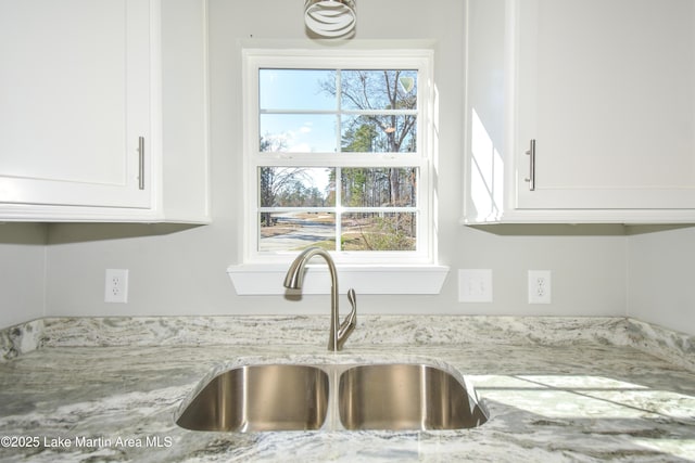 kitchen with white cabinetry, sink, and light stone counters