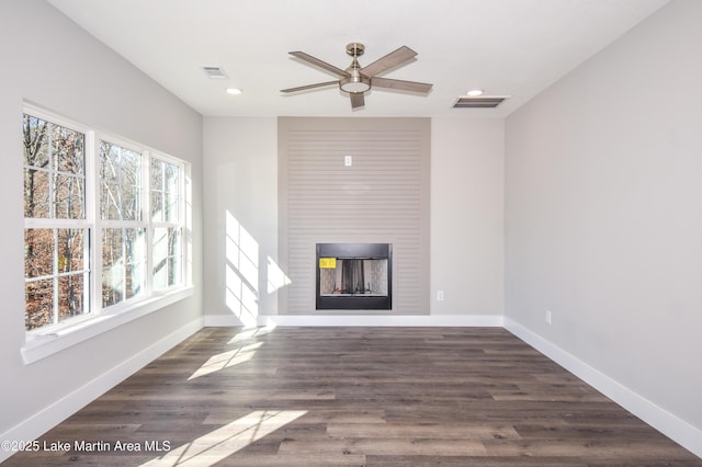 unfurnished living room with ceiling fan, a fireplace, and dark wood-type flooring