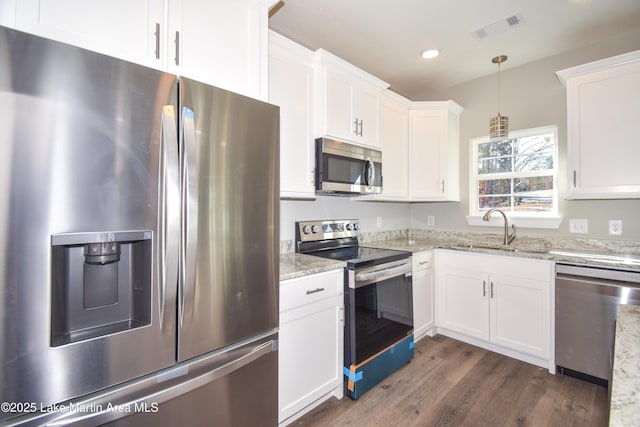 kitchen with light stone countertops, appliances with stainless steel finishes, white cabinetry, and sink