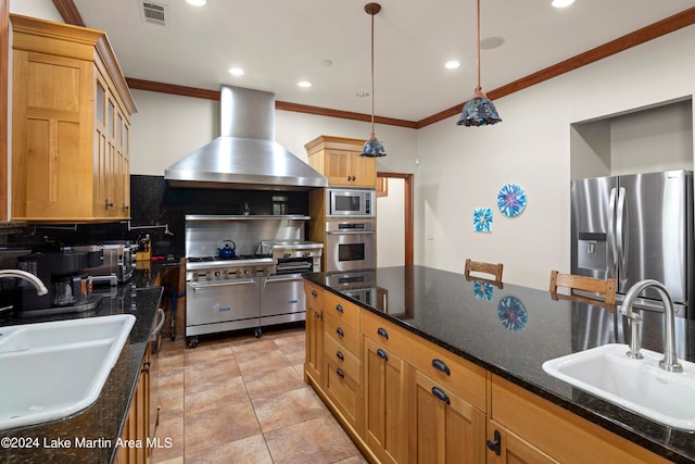 kitchen with sink, wall chimney exhaust hood, pendant lighting, and appliances with stainless steel finishes