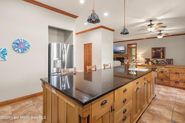 kitchen with dark stone counters, stainless steel fridge, sink, and pendant lighting