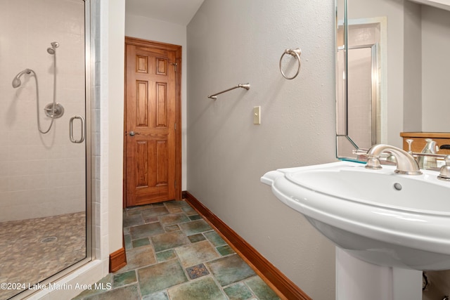 bathroom with a shower with door and sink