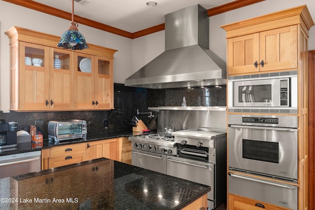 kitchen featuring appliances with stainless steel finishes, tasteful backsplash, dark stone counters, ornamental molding, and wall chimney exhaust hood