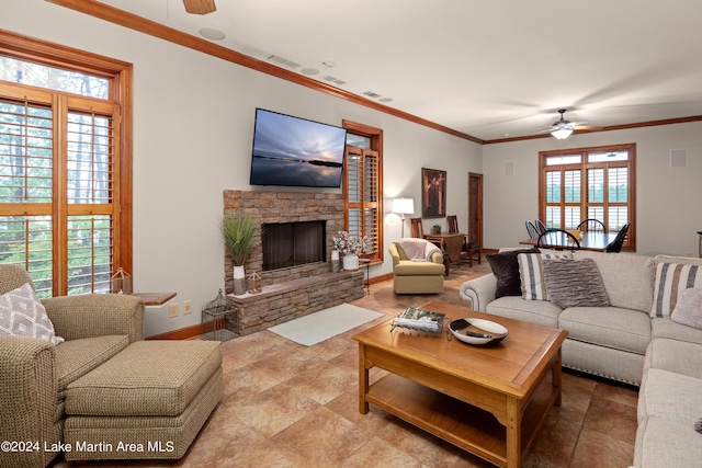 living room with ceiling fan, a stone fireplace, and ornamental molding