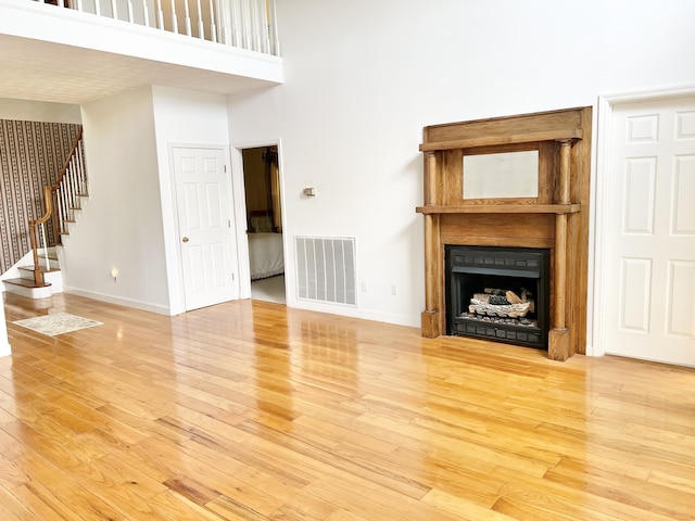1370 County Road 759, Clanton, AL 35045 - unfurnished living room with light wood-style floors, stairway, a towering ceiling, and a fireplace