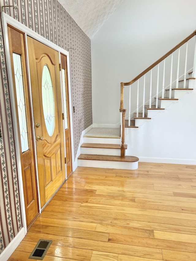 1370 County Road 759, Clanton, AL 35045 - foyer entrance with wallpapered walls, stairway, light wood-style floors, and a textured ceiling
