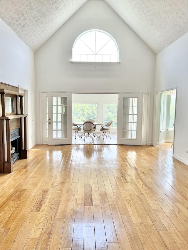 1370 County Road 759, Clanton, AL 35045 - unfurnished living room with high vaulted ceiling, a fireplace, hardwood / wood-style floors, a textured ceiling, and healthy amount of natural light