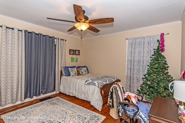 bedroom with ceiling fan, crown molding, and hardwood / wood-style flooring