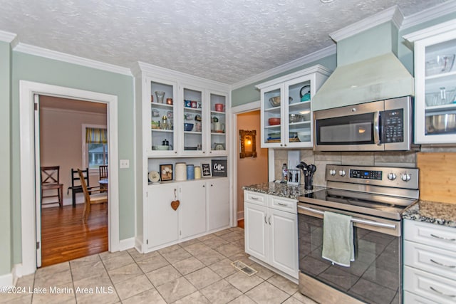 kitchen featuring light tile patterned flooring, dark stone countertops, white cabinetry, and stainless steel appliances