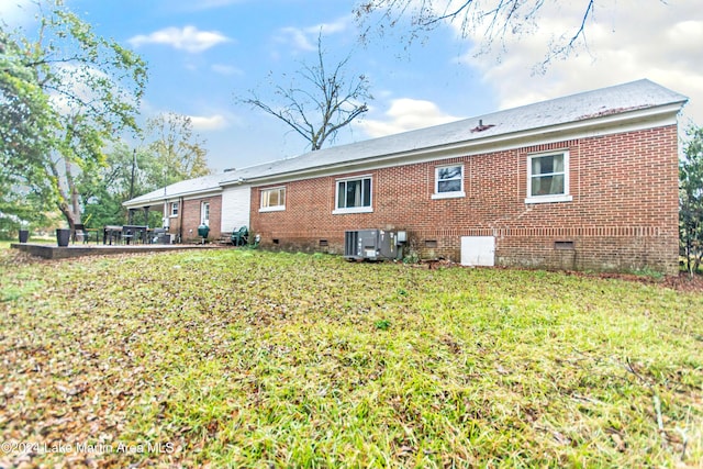 back of property with a yard and central AC