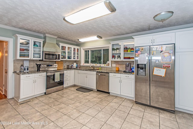 kitchen with decorative backsplash, stainless steel appliances, white cabinetry, and dark stone counters