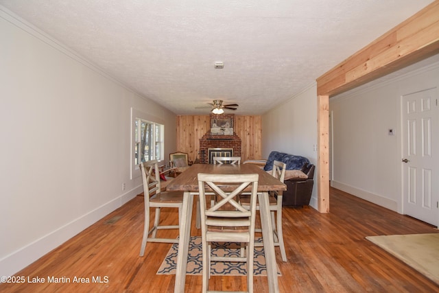 dining room with hardwood / wood-style flooring, ceiling fan, crown molding, and a textured ceiling