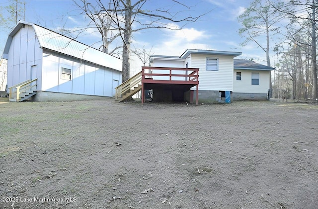 back of property with entry steps, a deck, stairs, and a gambrel roof