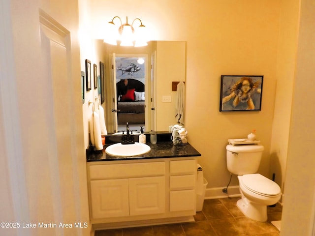 ensuite bathroom with toilet, ensuite bathroom, vanity, baseboards, and tile patterned floors