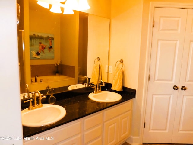 bathroom with a garden tub, double vanity, a closet, and a sink