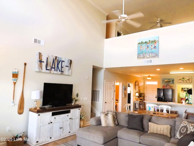 living area featuring ceiling fan, a towering ceiling, and visible vents