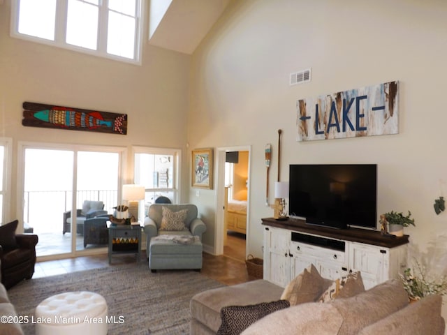 living area featuring tile patterned flooring, a high ceiling, and visible vents