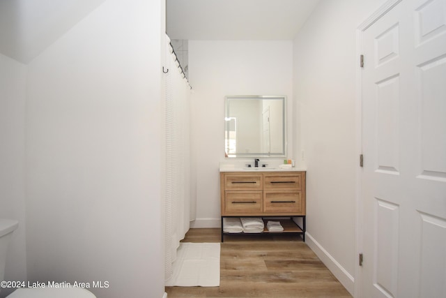 full bathroom with toilet, baseboards, wood finished floors, and vanity