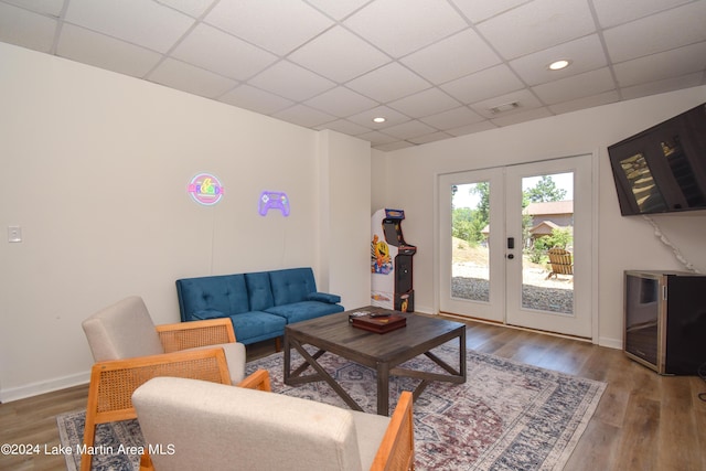 living room with a paneled ceiling, wood finished floors, visible vents, baseboards, and french doors