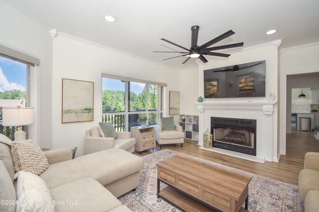 living room with recessed lighting, a brick fireplace, wood finished floors, and crown molding